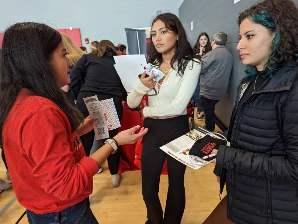 Maria Ramos discusses the World Languages program with two high school students