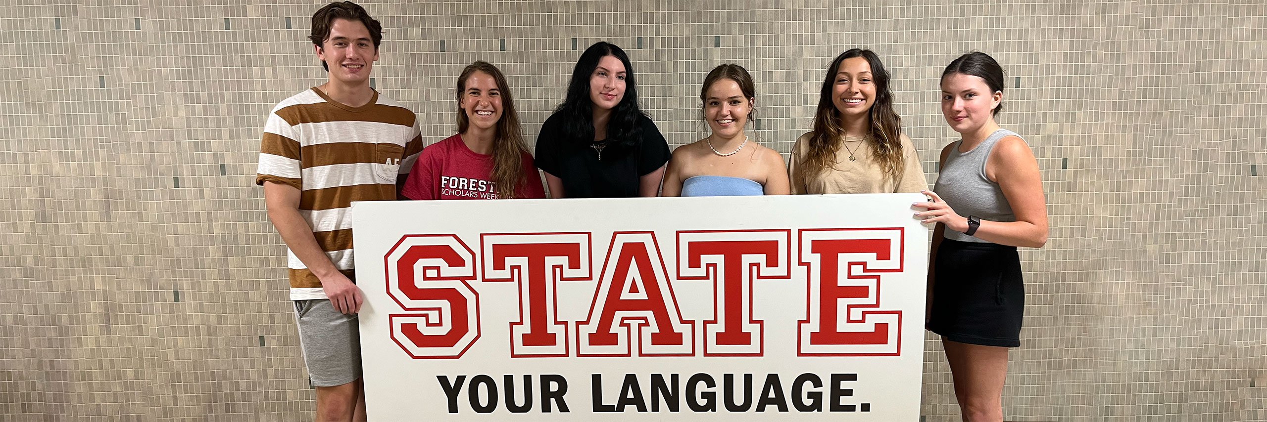 Students holding a sign witht the words State Your Language